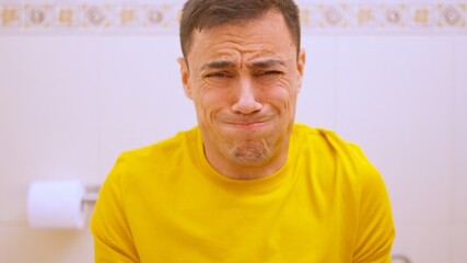 Obraz premium Man straining on toilet experiencing constipation and discomfort