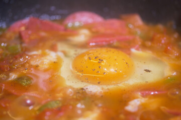 Cooking egg with vegetables in a skillet on the stove