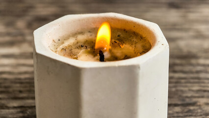 Close-up of a Wax Candle with a Flickering Flame in a Concrete Pot
