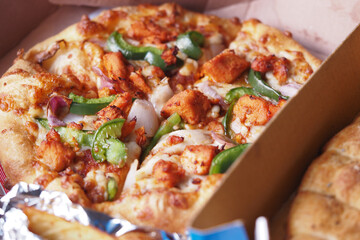 Delicious pizza topped with chicken and vegetables in a takeout box