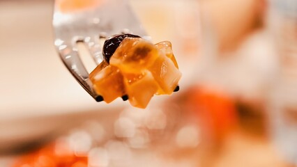 A close-up shot shows a cube of orange jelly dessert, highlighting its texture and presentation. Focusing on the details of the sweet treat, highlighting its appeal.