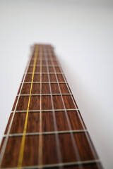 The guitar neck is shown in close-up, shot from below. The guitar neck is brown, with a wooden...