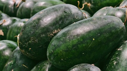 A close up shot displaying pile of fresh, dark green watermelons