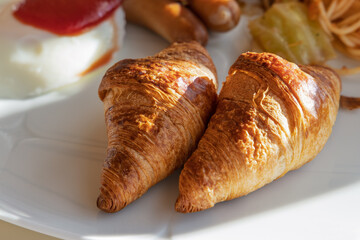 白い皿に乗った朝食とクロワッサン
