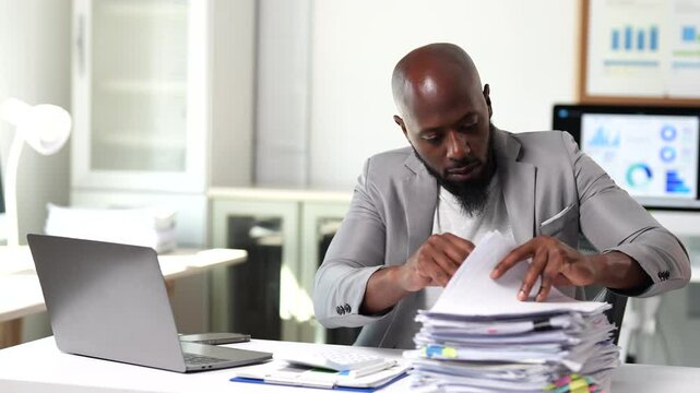 Office worker meticulously reviewing a substantial pile of documents, potentially searching for specific information or organizing paperwork