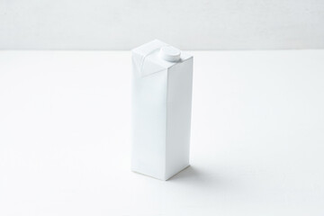Minimalistic White Carton Milk Box Sitting on a Clean, Light-Colored Surface in a Well-Lit Space