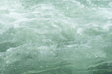 Blue water with ripples on the surface. Defocus blurred transparent blue colored clear calm water surface texture with splashes and bubbles. Water waves with shining pattern texture background.