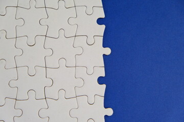Obraz premium white jigsaw puzzle with missing puzzle for a text template. Above photo of isolated on the blue background