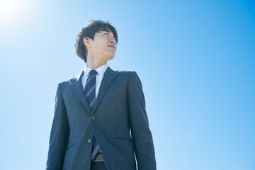 空に向かって立つスーツを着た男性