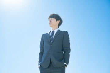 空に向かって立つスーツを着た男性