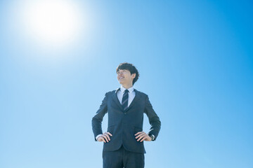 空に向かって立つスーツを着た男性