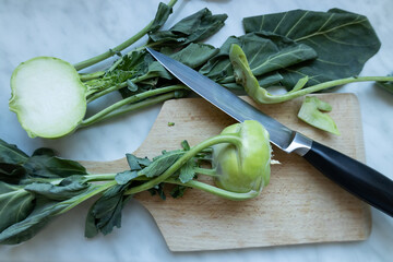 Fresh kohlrabi on a cutting board with a knife, featuring a halved kohlrabi showing its cut surface.