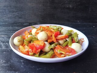 stir-fried green beans with vegetables and egg quality on plate with black wooden table background, high angle view 