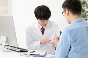 患者の手を見る医者