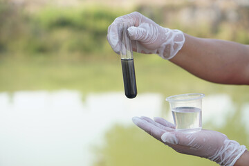 Close up scientist hand hold glass tube that contains sample of water to do science experiment....