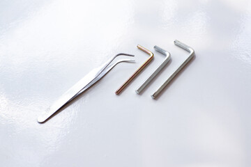 Three hexagon L key set and a pair of tweezers clamp on a white board