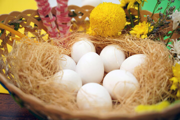 A basket with fresh eggs and vibrant flowers on a table for Easter