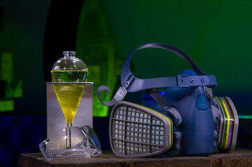Laboratory safety equipment with respirator mask and chemical separatory funnel containing yellow...