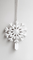 Elegant white snowflake ornament hanging against a soft gray background, showcasing intricate geometric patterns and a festive mood.