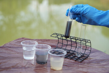 Close up scientist hand hold glass tube that contains sample of water to do science experiment....