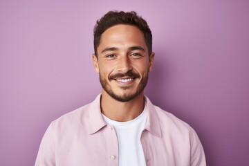 Obraz premium Portrait of handsome young man looking at camera and smiling while standing against purple background