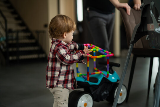 Little toddler baby boy playing with development toys for developing movements in different colors using family and friends meetup time. Toddler party children having fun with toys