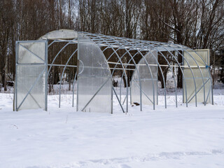 The metal frame of the greenhouse in winter. Preparing greenhouses for winter or spring. Gardeners...