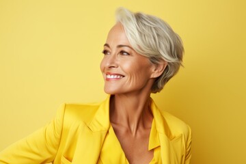 Portrait of smiling senior businesswoman in yellow jacket on yellow background