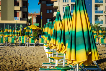 Gli ombrelloni colorati e le sedie a sdraio di uno stabilimento balneare pronte per una giornata di...
