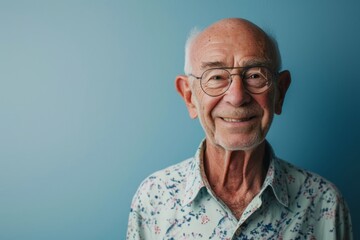 Obraz premium Portrait of a smiling senior man wearing glasses against a blue background