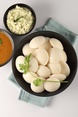 Idli Sambar, Famous South Indian Dish in a black ceramic cutlery on white background