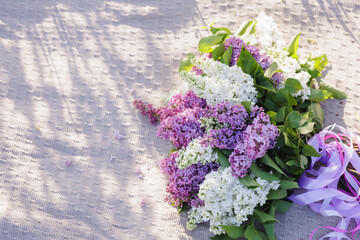 Beautiful lilac flowers in soft sunlight on a knitted fabric background, romantic spring floral composition, nature and seasonal freshness.