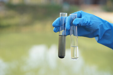 Close up scientist hand hold glass tube that contains sample of water to do science experiment....
