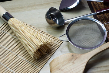 Spatula for 2 types of cooking, both frying and stir-frying, and other cooking equipment. Ready to use on a wooden cutting board on a white surface in the kitchen
