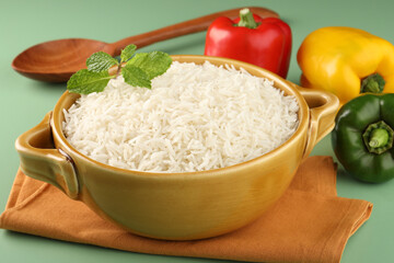 Rice in ceramic cutlery on green background