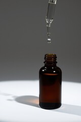 Serum drop falling into an amber glass bottle. Beauty essential oil for wellness and skincare ritual.
