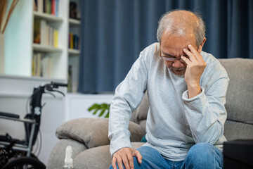 Asian mature old man sitting on sofa headache at home in living room, Depressed senior man unhappy...