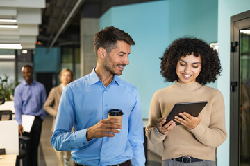 Fototapeta premium Two business people discussing work together using a tablet in a modern office