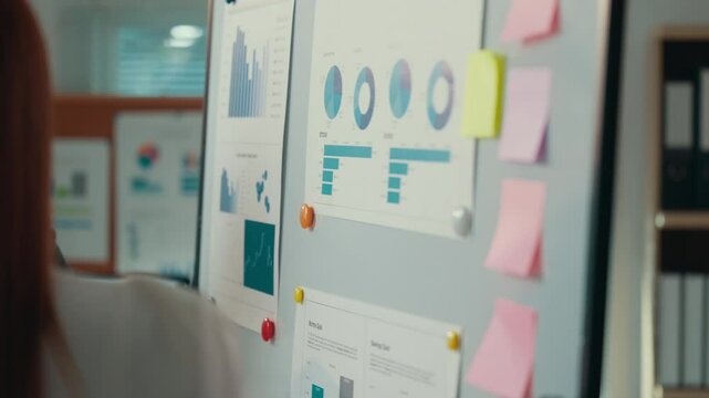 Professional businesswoman reviewing financial data, sharing strategic insights with team member in modern corporate workspace