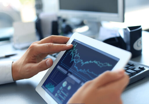 Business person analyzing financial statistics displayed on the tablet screen
