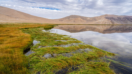Scenic landscape view with colorful mountains reflection in high-altitude Bulunkul lake, Murghab,...