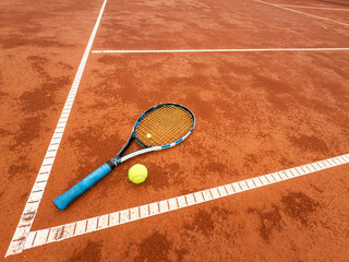 Tennis ball and racket on a clay court close-up
