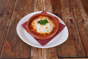 A bowl of food with a red napkin on top lasagna