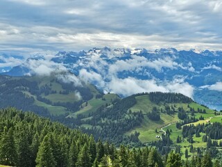 A stunning summer view from Mount Rigi, often referred to as the "Queen of the Mountains," offering panoramic vistas of the Swiss Alps and surrounding lakes. This image captures the lush green meadows
