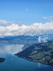 A stunning summer view from Mount Rigi, often referred to as the "Queen of the Mountains," offering panoramic vistas of the Swiss Alps and surrounding lakes. This image captures the lush green meadows