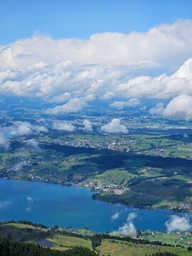 A stunning summer view from Mount Rigi, often referred to as the "Queen of the Mountains," offering panoramic vistas of the Swiss Alps and surrounding lakes. This image captures the lush green meadows