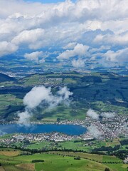 A stunning summer view from Mount Rigi, often referred to as the "Queen of the Mountains," offering panoramic vistas of the Swiss Alps and surrounding lakes. This image captures the lush green meadows