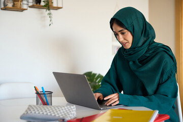 Young muslim woman working from home on laptop