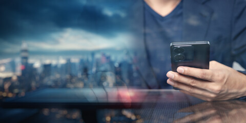 Person Using Smartphone with Cityscape Background at Sunset