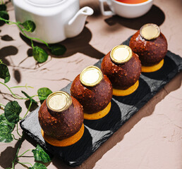 Unique dessert presented on a black slate with tea in the background